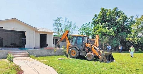 A bulldozer readies to raze a structure at a farmhouse at Noida | Express