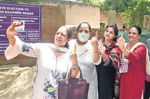 Women click selfies after casting their votes at a polling station.