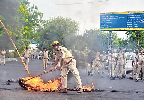 Police try to douse tyres burnt during a protest against killing of Kanhaiya Lal in Udaipur, in Jodhpur. (Photo | PTI)