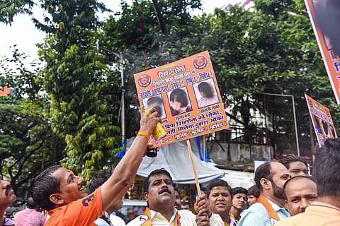 'Shiv Sainiks' or Shiv Sena workers deface a placard depicting rebel MLAs from the party as they gather to support Maharashtra CM Uddhav Thackeray. (Photo | PTI)