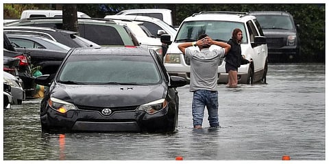 A driver climbs out of his stalled car after he tried to move it to higher ground from the flooded parking lot at Sheridan Apartments in Dania Beach on Saturday, June 4, 2022 (Photo | AP)