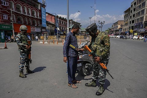 An Indian paramilitary soldier checks a civilian as they guard in Srinagar. (Photo | AP)