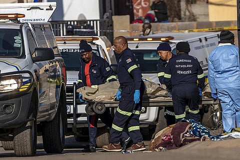 A body is removed from the scene of an overnight bar shooting in Soweto, South Africa. (Photo | AP)
