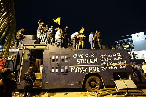 Protesters stand on a vandalised police water canon truck and shout slogans at the entrance to president's official residence in Colombo, Sri Lanka, on July 9, 2022. (Photo | AP)