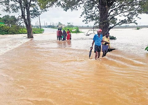 People cross the flooded road from Eturunagaram to Brahmanapally in Mulugu district. (Photo Express)
