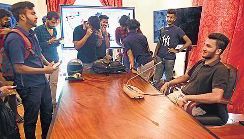 A protester poses for pictures while seated on Sri Lankan President’s chair at the presidential palace in Colombo on Sunday | AFP