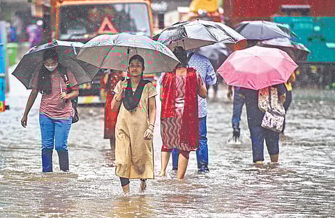 People wade through a flooded road in Mumbai on Tuesday | PTI