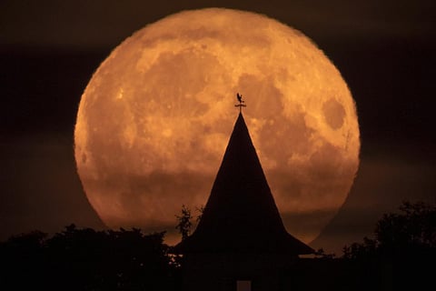 The full moon rises over a private house in the village of Putilovo, 70 kilometeres east of St. Petersburg, Russia on July 13, 2022. (Photo | AP)