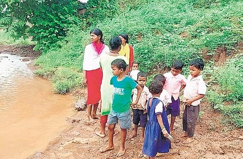 Children of Gopisahi await to be carried to other side of the nullah, in Koida. (Photo| EPS)
