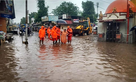 National Disaster Response Force (NDRF) personnel evacuate an elderly person from a flood-hit residential colony following heavy monsoon rains, in Navsari, on July 14, 2022. (Photo | PTI)