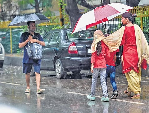 Pedestrians use umbrellas to cover themselves during monsoon rain. (Photo | PTI)