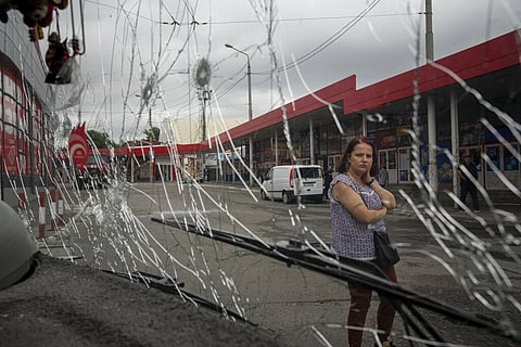 A woman looks at a trolleybus damaged by Russian shelling. (Photo | AP)