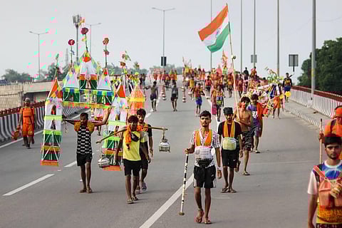 Kanwariyas (Lord Shiva devotees) walk down the road during their pilgrimage in the holy month of 'Shravan', in Meerut, Saturday, July 23, 2022. (Photo | PTI)
