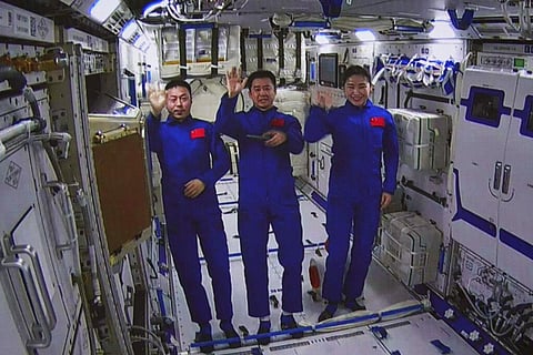 An image taken off the screen at the Beijing Aerospace Control Center shows Chinese astronauts from left, Cai Xuzhe, Chen Dong and Liu Yang wave from inside the Wentian lab module. (Photo | AP)