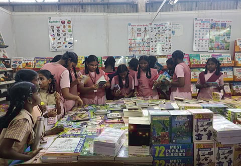 School students reading books at a stall in Thanjavur book fair on Monday