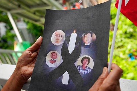 A Myanmar national living in Thailand holds the pictures of the executed political prisoners in Myanmar, as they protest outside Myanmar's embassy in Bangkok, on July 26, 2022. (Photo | AP)