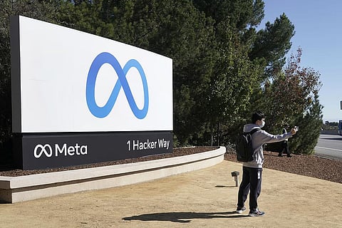 A Facebook employee take a selfie in front the company's new name and logo outside its headquarters in Menlo Park, California. (File Photo | AP)