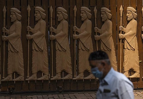 A Parsi man walks next to a bas-relief depicting early Zoroastrians at a Parsi colony on Nowruz, the Parsi New Year, in Mumbai, India. (Photo | AP)