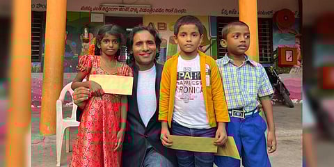 Yeruva Sairam, an NRI from USA, with some of the school students his trust is sponsoring, at a village in Guntur district | Express