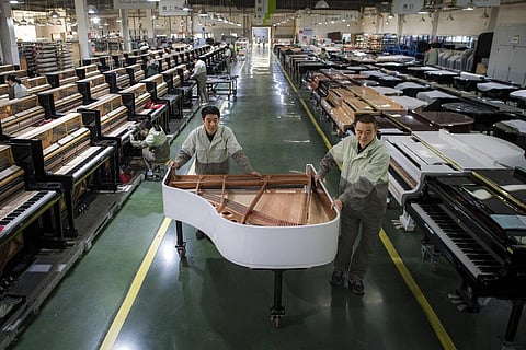 Workers transfer a half-assembled piano at a production factory of Parsons Music Corporation in Yichang, central China's Hubei Province(File photo | AP)