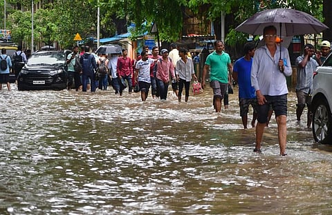 Commuters wade through a waterlogged street after heavy monsoon rainfall in Mumbai, Wednesday, July 6, 2022. (Photo | PTI)