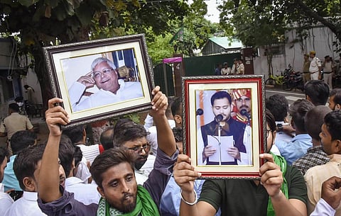 RJD supporters holding portraits of party chief Lalu Prasad and senior leader Tejaswi Yadav gather outside the residence of former CM Rabri Devi, in Patna. (Photo | PTI)