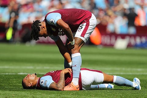 Aston Villa's Tyrone Mings (up) checks on Diego Carlos as he lays on the pitch after hurting himself during an English Premier League match on August 13, 2022. (Photo | AFP)