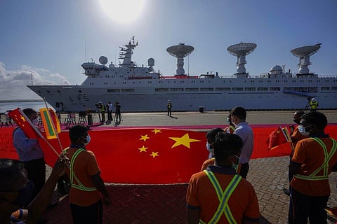 Sri Lankan port workers hold a Chinese national flag to welcome Chinese research ship Yuan Wang 5 as it arrives in Hambantota International Port in Hambantota, Sri Lanka(Photo | AP)