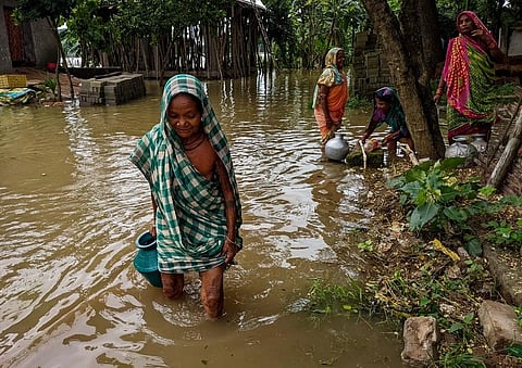 An elderly woman carries drinking water in knee-deep water at Bandhahata village in Athagarh (Photo | Debadatta Mallick, EPS)