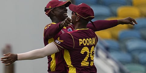 West Indies' Shamarh Brooks celebrates with captain Nicholas Pooran after taking the catch to dismiss New Zealand's Devon Conway.(Photo | AP)