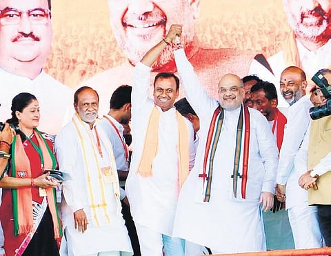 Amit Shah raises the hand of Komatireddy Rajagopal Reddy as other BJP leaders look on during ‘Munugode Samarabheri’ at Munugode on Sunday