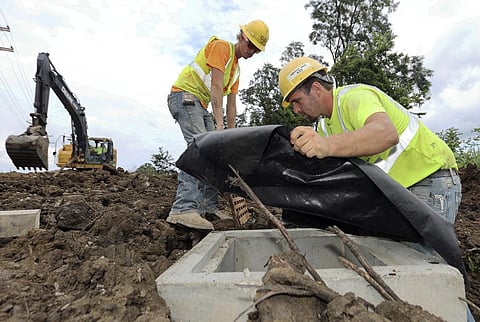 Taylor Purdy, right, a pipe layer, and colleague Adam Clary install temporary silt protection for a catch basin near a new Intel semiconductor manufacturing plant. (Photo | AP)