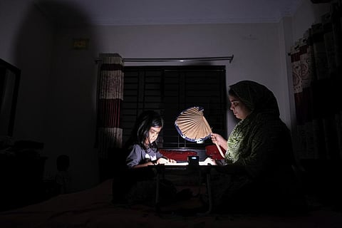 A Bangladeshi woman uses a traditional hand fan as she assists her daughter in her studies during a power cut at their home in Pilkhana area, Dhaka, Bangladesh, Tuesday, Aug.23, 2022. (Photo | AP)