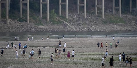 People walk along the dry riverbed of the Jialing River, a tributary of the Yangtze, in southwestern China's Chongqing Municipality, Saturday, Aug. 20, 2022.(Photo | AP)