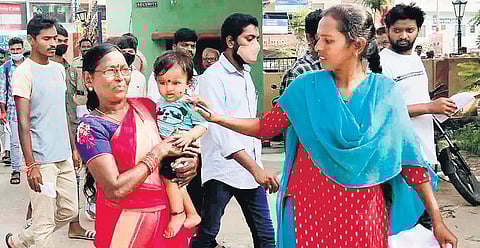 A candidate hands her child to her mother before entering the examination centre set up at the Hanamkonda Arts and Science College to take the recruitment test on Sunday