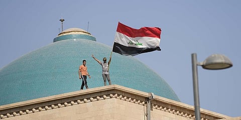 Supporters of Shiite cleric Muqtada al-Sadr wave a national flag from the roof of the Government Palace during a demonstration in Baghdad, Iraq, Monday, Aug. 29, 2022.(Photo | AP)