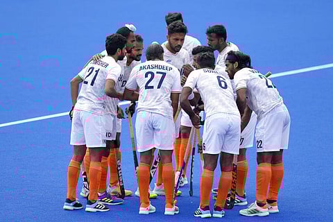 The India players gather around Harmanpreet Singh to celebrate after he scores his sides third goal during the hockey match between India and Wales. (Photo | AP)