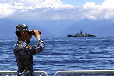 A People's Liberation Army member looks through binoculars during military exercises as Taiwan’s frigate Lan Yang is seen at the rear, on Friday, Aug. 5, 2022. (Photo | AP)