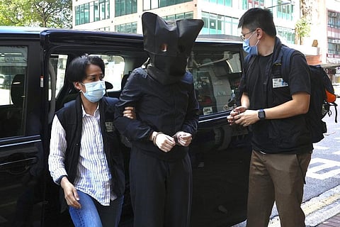 A hooded suspect is accompanied by police officers to search evidence at office in Hong Kong Thursday, July 22, 2021. (File Photo | AP)