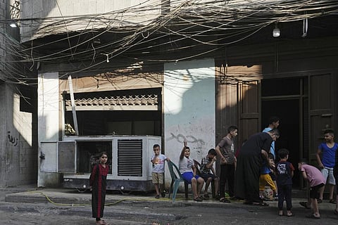 Children hang out near an electricity generator under electricity distribution wires in the Shati refugee camp, Gaza City, July 8, 2022. (Photo | AP)
