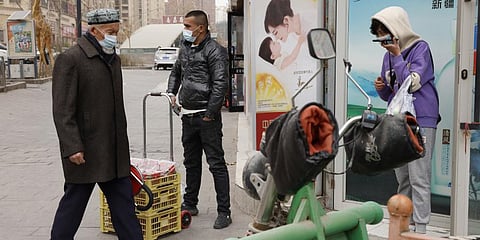 Residents wearing masks walk along the streets of Aksu in western China's Xinjiang region on Thursday, March 18, 2021. (File Photo | AP)