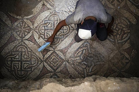 A Palestinian sweeps dust off parts of a Byzantine-era mosaic floor that was uncovered by a farmer in Bureij in central Gaza Strip. (Photo | AP)