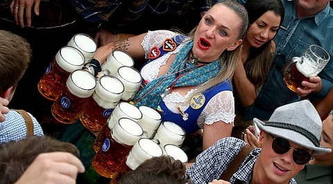 A waitress holds twelve glasses of beer during the opening of the 186th 'Oktoberfest' beer festival in Munich, Germany. ( Photo |AP)