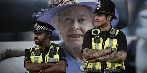 Police officers are backdropped by a photograph of Queen Elizabeth II in London, Friday, Sept.16, 2022.(Photo | AP)