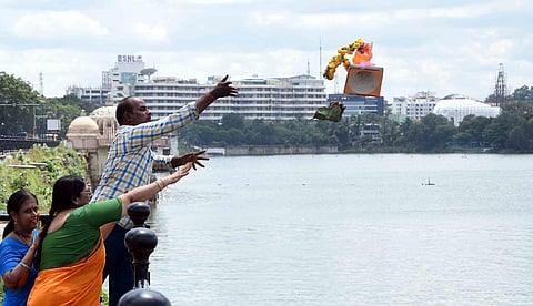 A man throws an idol into the Hussainsagar in Hyderabad on Thursday. (Photo | RVK Rao)