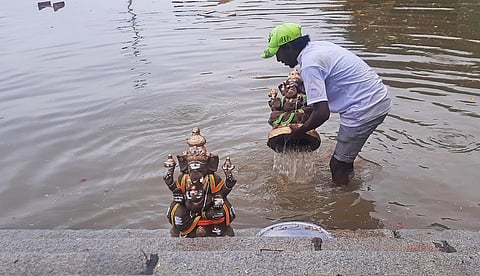 A man immerses Ganesha idols in Ulsoor Lake, Bengaluru on Thursday. (Photo | Vinod kumar T, EPS)