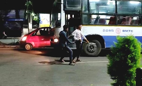 A video grab shows some youths brandishing a sword-like object and charging at their victims, even as traffic moves around them, near Balekundri Circle on Monday. (Photo | Express)