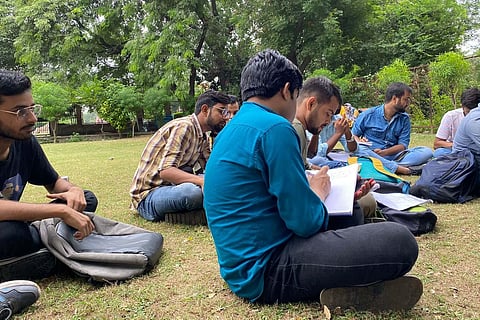 Students of Masters in Mass Media (Hindi) at the Jamia Millia Islamia University were forced to study outside in a park due to improper classroom. (Photo | Express)