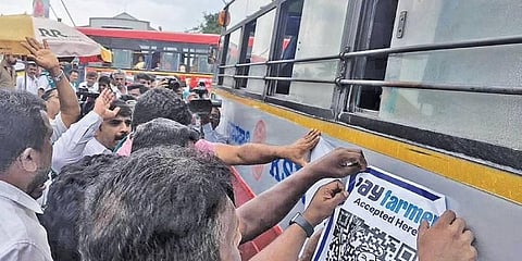 Members of the Karnataka Rajya Raitha Sangha paste ‘Payfarmer’ posters on a KSRTC bus in Mandya on Monday | express