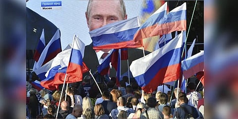 People watch on a large screen, as Russian President Vladimir Putin delivers his speech after a ceremony to sign the treaties for four regions of Ukraine to join Russia. (Photo | AP)